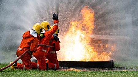 Firefighters or Firemen use extinguisher and spray high pressure water from hose to control fire.Firefighter team training to control fire not to spreading out in gas and oil fire accident simulation.
